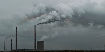 Smoke billowing from chimneys at a power plant.