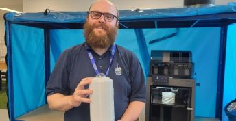 Ben Pickering stands holding the camera he has built to enhance weather forecasting from local weather stations.