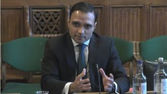 Dr Stuart Flint sitting at a desk, speaking during the Health and Social Care Committee meeting inquiry