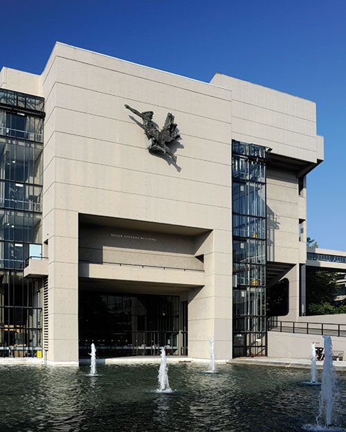 The Spirit of Enterprise, a flying figure, is pictured on the front of the Roger Stevens building.Below is a large water feature with fountains.