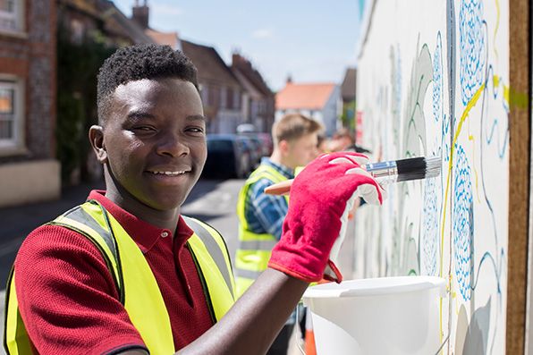 A teenage paints a community art installation.