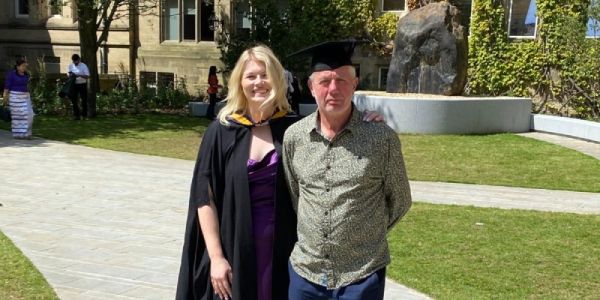 Rachel and Hugh standing together at Rachel's MBA graduation in July 2024.