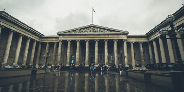 雨天，大英博物馆雄伟的立柱和前院，建筑外有人。