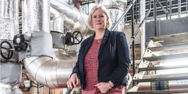 Professor Cath Noakes standing in front of large, silver ventilation ducts