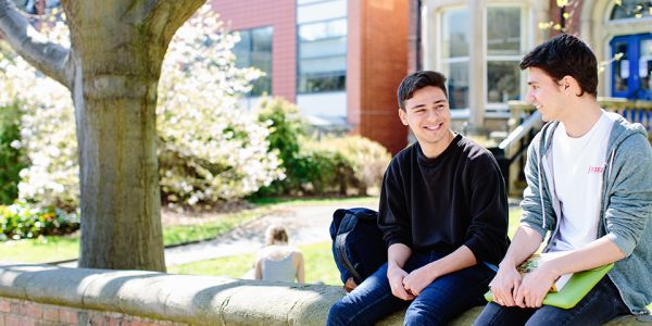 Two students sitting on a wall outside on campus
