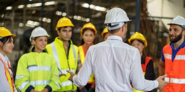 An Engineering Manager overseeing a team of engineers wearing high-visibility jackets and hard hats on a construction site.