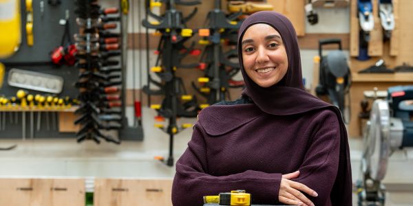 Fareda stands with her arms folded in the middle of a workshop