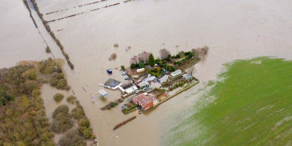 Aerial view of a flooded house, a forest and field
