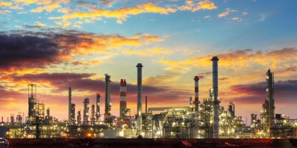 industrial plant with tall chimneys billowing smoke, at dusk