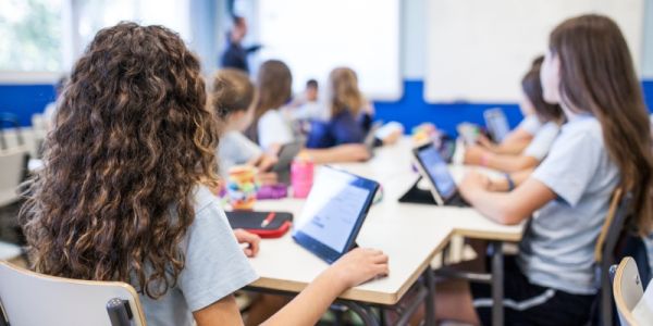 School children in a classroom facing a teacher at the front of the class