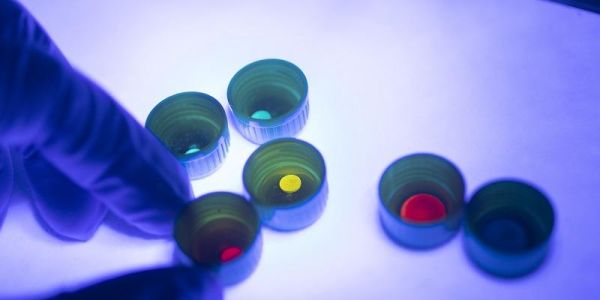 Examples of the fabricated glass composite shown under a UV light (black light), revealing the emission of bright and pure colours.