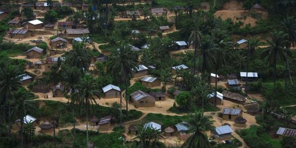 This is an aerial image of an African village showing small buildings on the side of a sandy track. There is no sign of major infrastructure development.