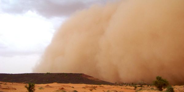 A giant dust cloud approaching the camera as it moves across a sandy and dust terrain