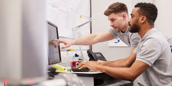 Two people looking at a computer screen together. One is pointing at the screen.