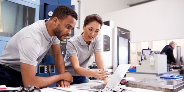 Two people in an engineering lab discussing something on a laptop.