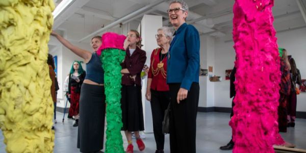 The Lord Mayor of Leeds Al Garthwaite and others look at bright pink and yellow sculptures, as a student explains the work