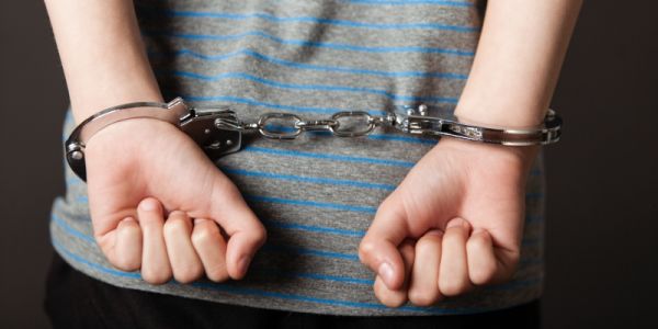 A child's arms in handcuffs