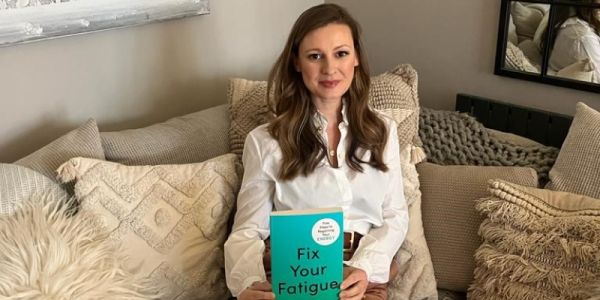 Karina Antram sits on sofa holding her book