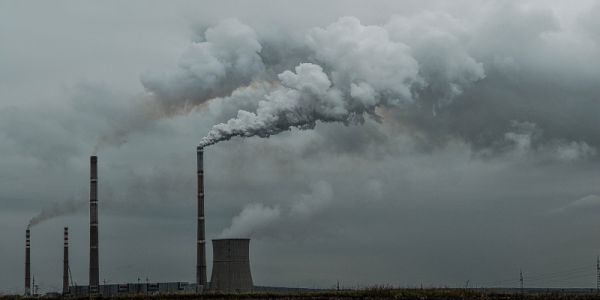 Smoke billowing from chimneys at a power plant.