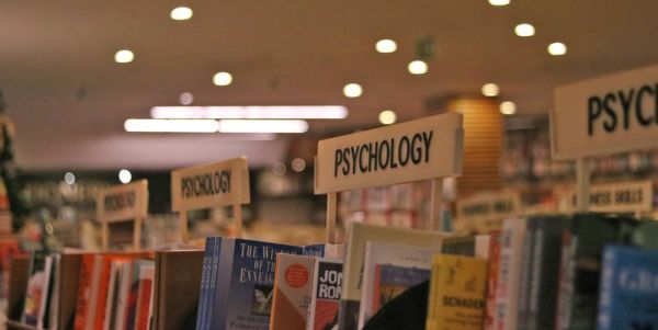 Shelves of books in a library with a sign above them that says 'Psychology'.