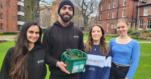 Compost-it creators Simrun Punjabi and Husain Alogaily stand with a caddy of vegetable waste with volunteers Orla Smith and Katherine Mustard