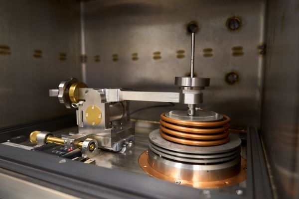 A close-up of the environmental tribometer, showing a metal heated sample stage and contact arm. 