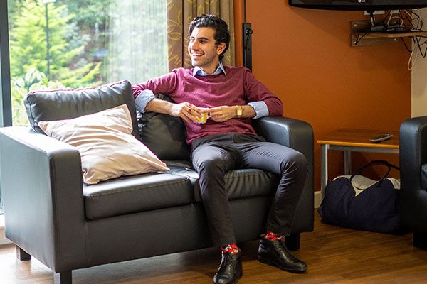 A student sits comfortably on a sofa in the communal area of a shared flat.