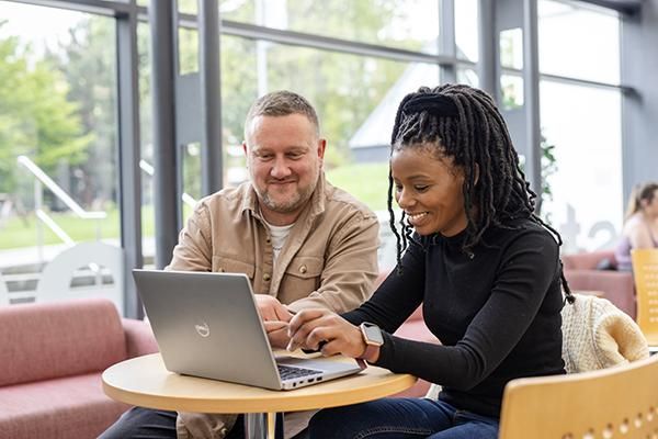 Two people sat working together on a laptop