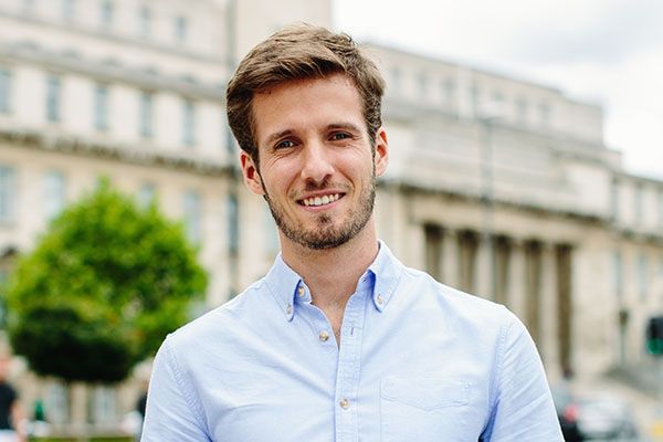 A postgraduate student stood in front of the large pillars of the Parkinson Building at the University of Leeds.