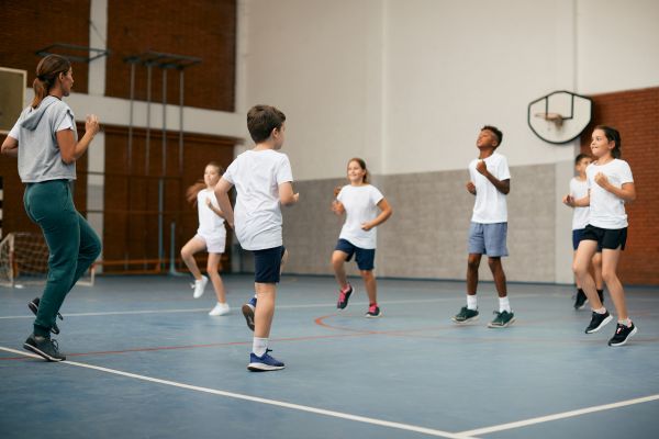 Children jogging on the spot in a sports hall.