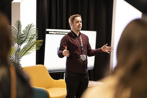 A student in a work placement talking in front of a display.