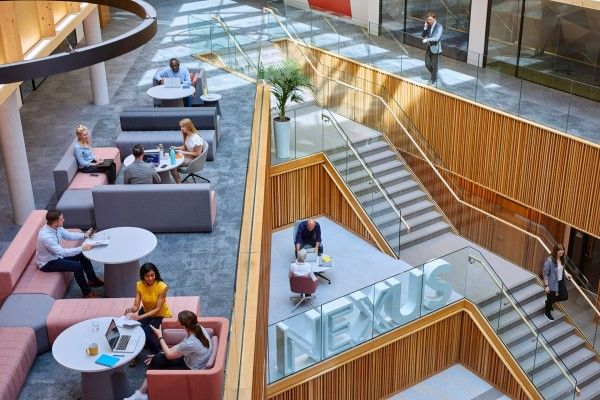 Looking down on an open area of the Nexus building with groups of adults sitting and working together.