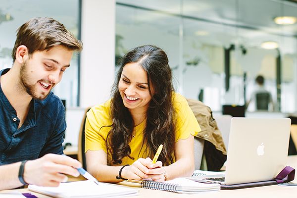 Two students sit by a laptop.