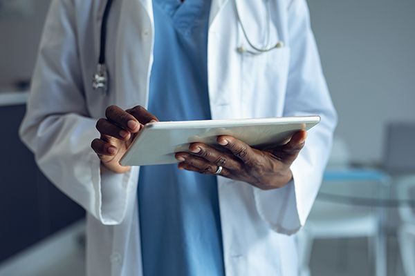 A clinician updates medical records on a hand-held tablet device