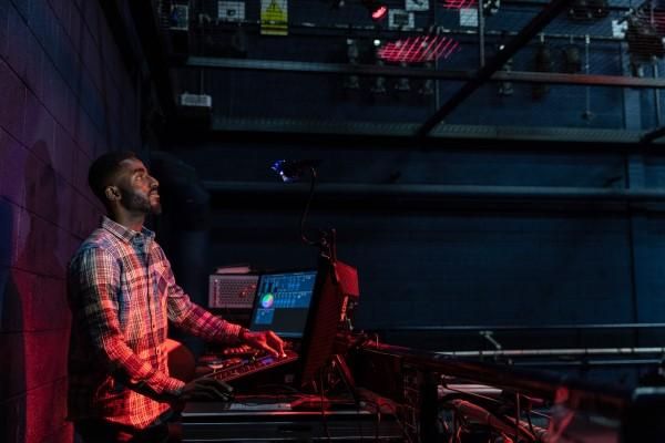 A student surveys a technical desk in a theatre space