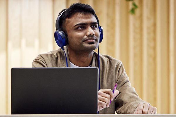 A student wearing headphones and using a laptop.