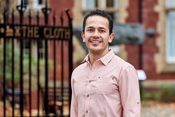 Emilio smiling, in front of the gates at Clothworker's court.