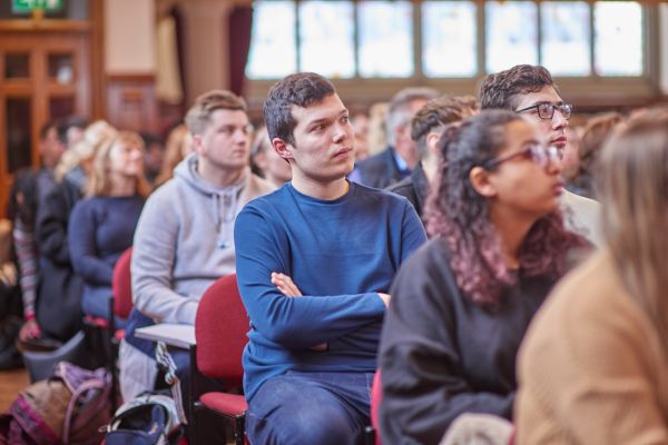 A prospective student attentively listens during a general talk in the Great Hall at the University of Leeds.