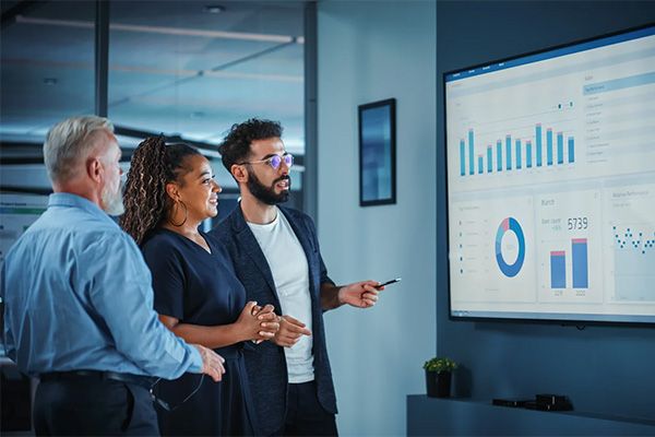 Three colleagues reviewing a data related screen.