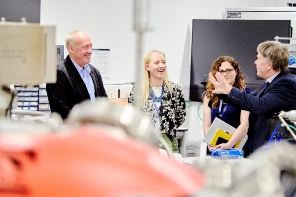 Chris Johnson stands in a laboratory talking to three members of the Bragg centre team.