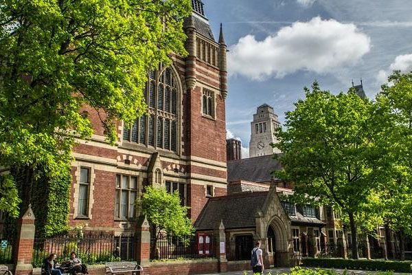 View of the Great Hall on University of Leeds campus. The sun is shining on the surrounding trees.