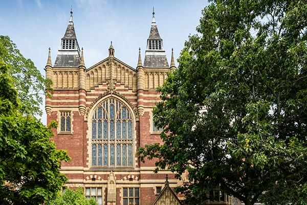 The front of the Great Hall surrounded by trees and a blue sky.