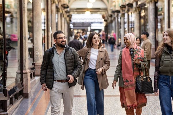 Four students walking and chatting in a beautiful Victorian shopping arcade in Leeds city centre