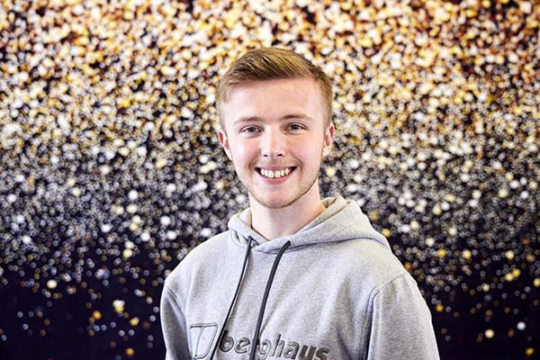 Portrait of Healthcliff Howard smiling in front of a starscape background.