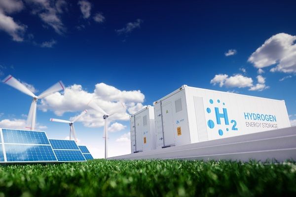 Two large shipping containers labelled hydrogen energy storage, next to wind turbines and solar panels
