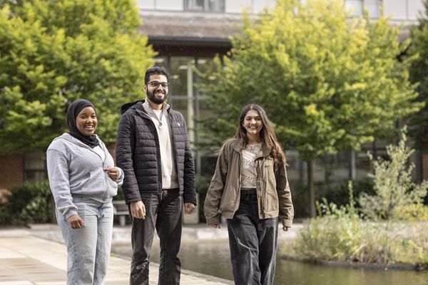 Three students walking in a green space on campus