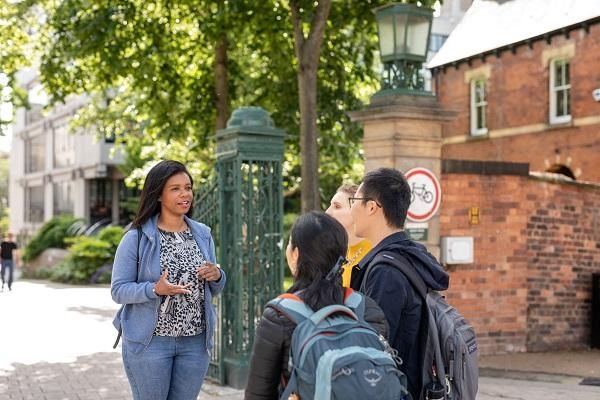 3 students listening to a guide on a campus tour at the University of Leeds.