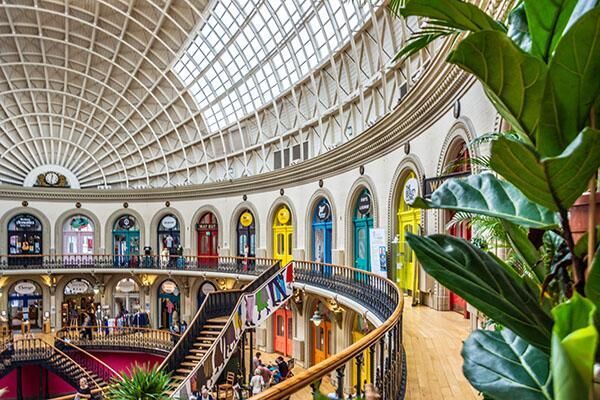The inside of Leeds Corn Exchange building showing a domed ceiling and colourful doors.