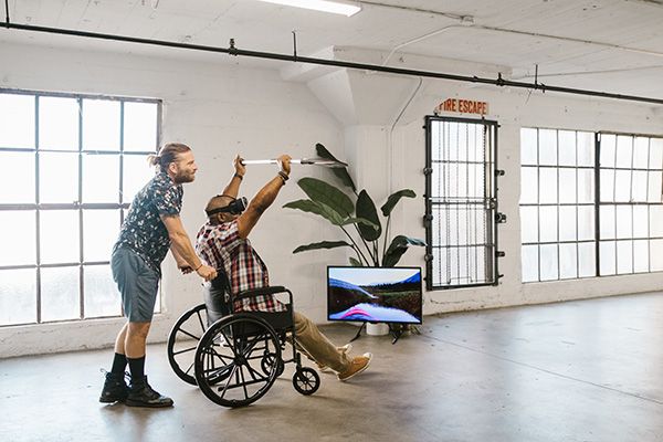 A wheelchair user using assistive technology with a person accompanying them.