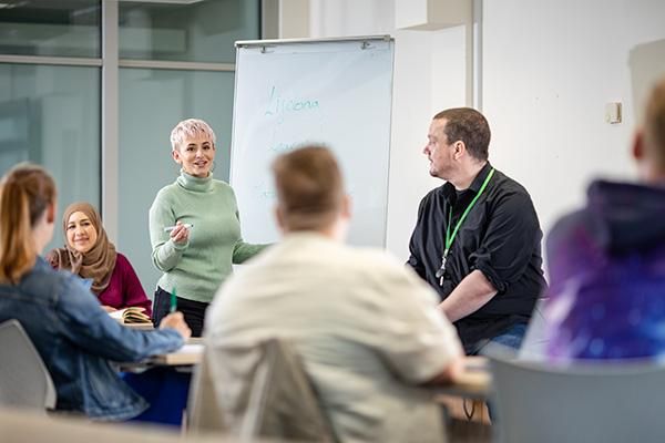 Two staff members next to a flip chart teaching a course to mature students